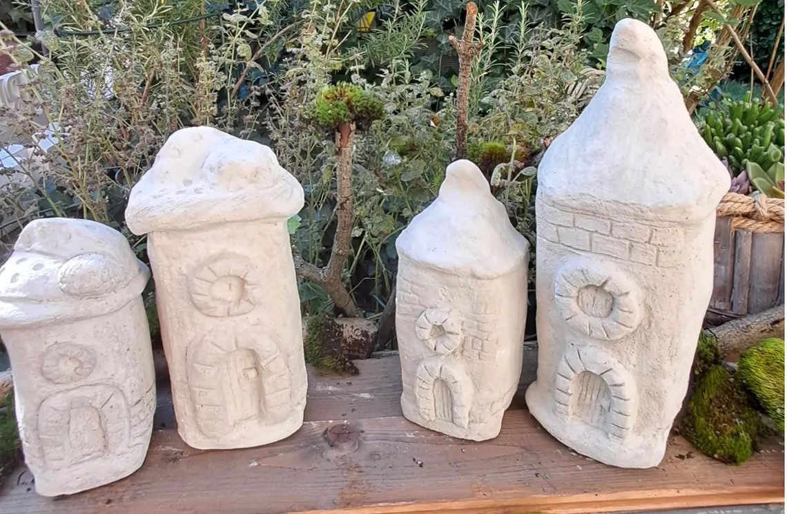 Handgemachte Betonhäuser mit Zipfelmütze als Gartendeko